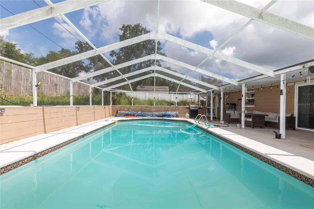 A rectangular swimming pool is enclosed by a white screen structure on a concrete patio — 841 BRENTWOOD DRIVE, LAKE WALES, FL