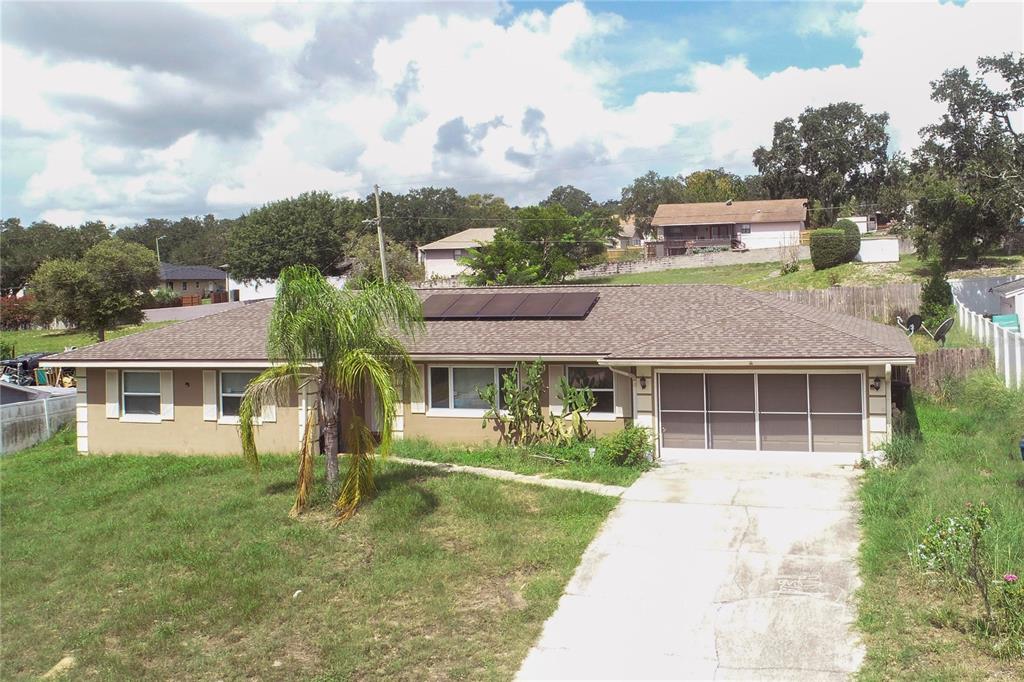 A single-story house with a brown shingled roof, solar panels, and a concrete driveway — 841 BRENTWOOD DRIVE, LAKE WALES, FL