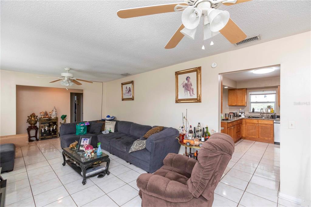 A living room with tile floors, a sectional sofa, a recliner, and an adjacent kitchen — 841 BRENTWOOD DRIVE, LAKE WALES, FL