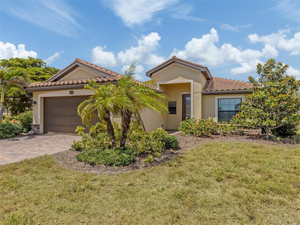 A single-story stucco house with a tile roof, a two-car garage, and front landscaping — 12490 CINQUETERRE DRIVE, VENICE, FL