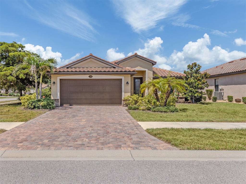 A single-story house with a brown garage door, tiled roof, and a paved driveway — 12490 CINQUETERRE DRIVE, VENICE, FL
