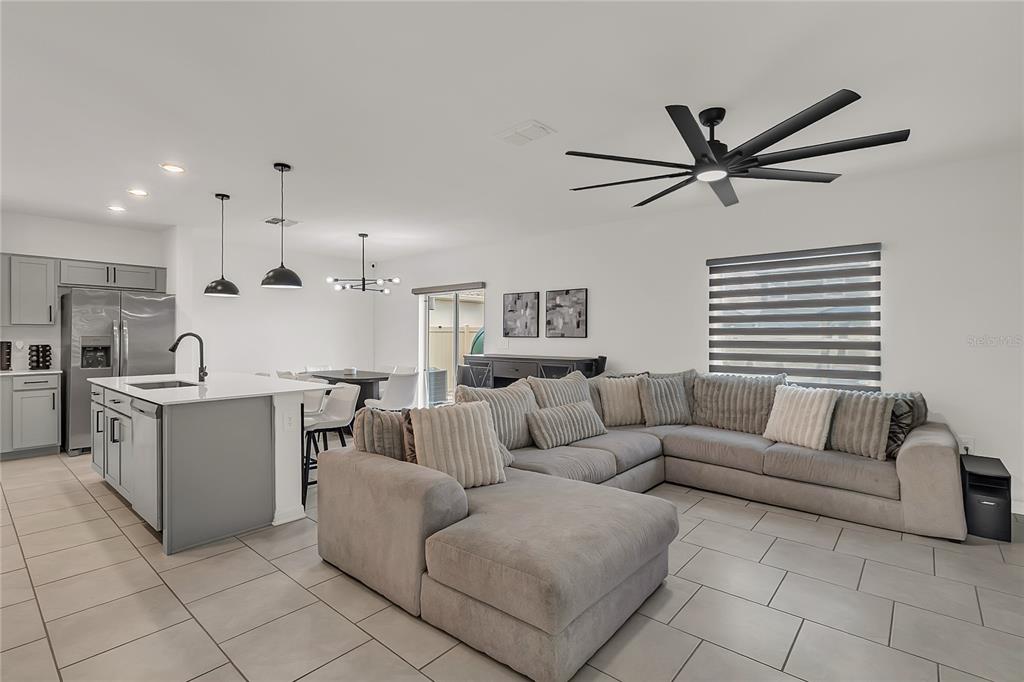 An open-concept kitchen and living area features a large gray sectional and kitchen island — 1325 DIEGO TERRACE, WINTER HAVEN, FL