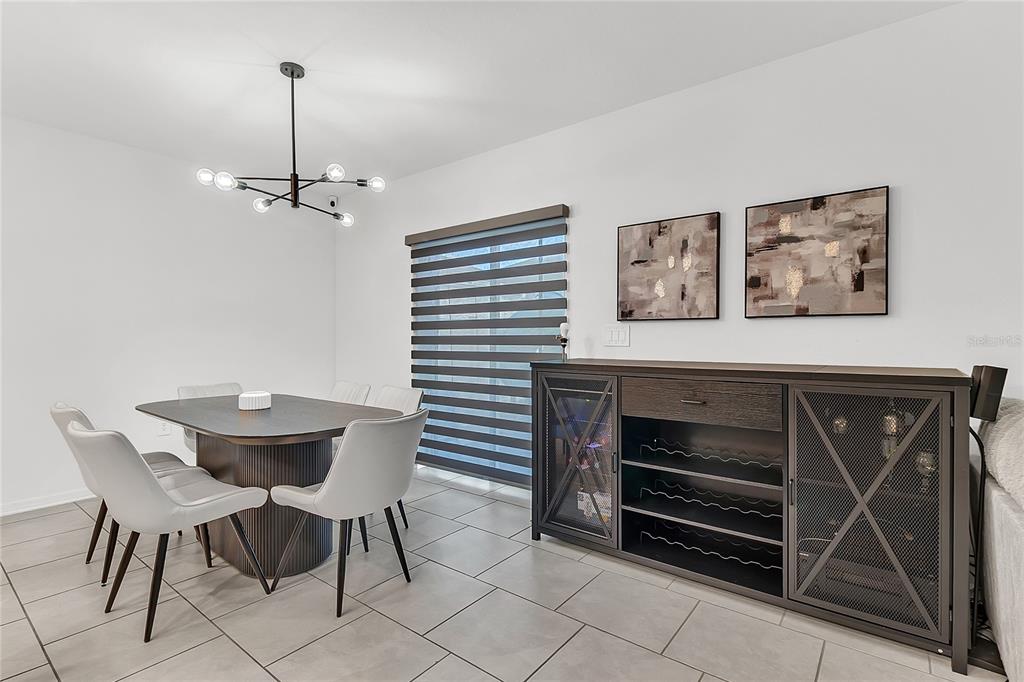A dining room features a modern chandelier, a dark table with chairs, and a sideboard — 1325 DIEGO TERRACE, WINTER HAVEN, FL