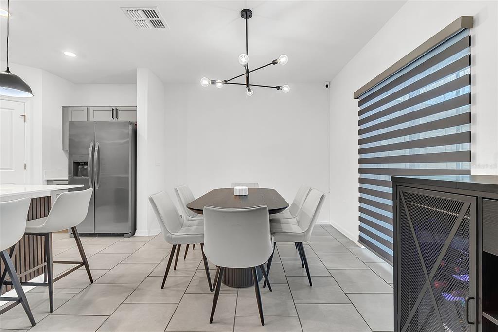 A dining area features a dark oval table, light gray chairs, and a modern chandelier — 1325 DIEGO TERRACE, WINTER HAVEN, FL