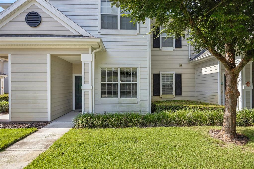 A two-story townhouse exterior features light-colored horizontal siding, a covered entryway, and a front lawn — 405 SOUTHERN PECAN CIRCLE UNIT 108, WINTER GARDEN, FL