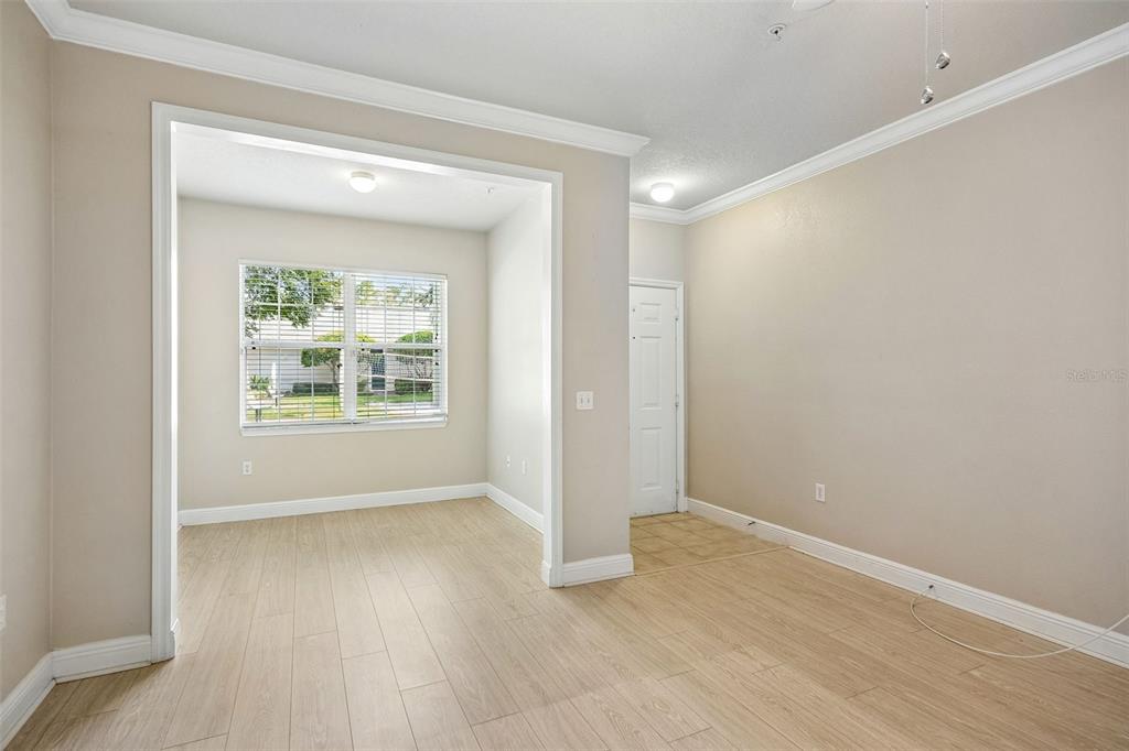 An empty room with light wood-look flooring, beige walls, and an arched entryway to a nook — 405 SOUTHERN PECAN CIRCLE UNIT 108, WINTER GARDEN, FL