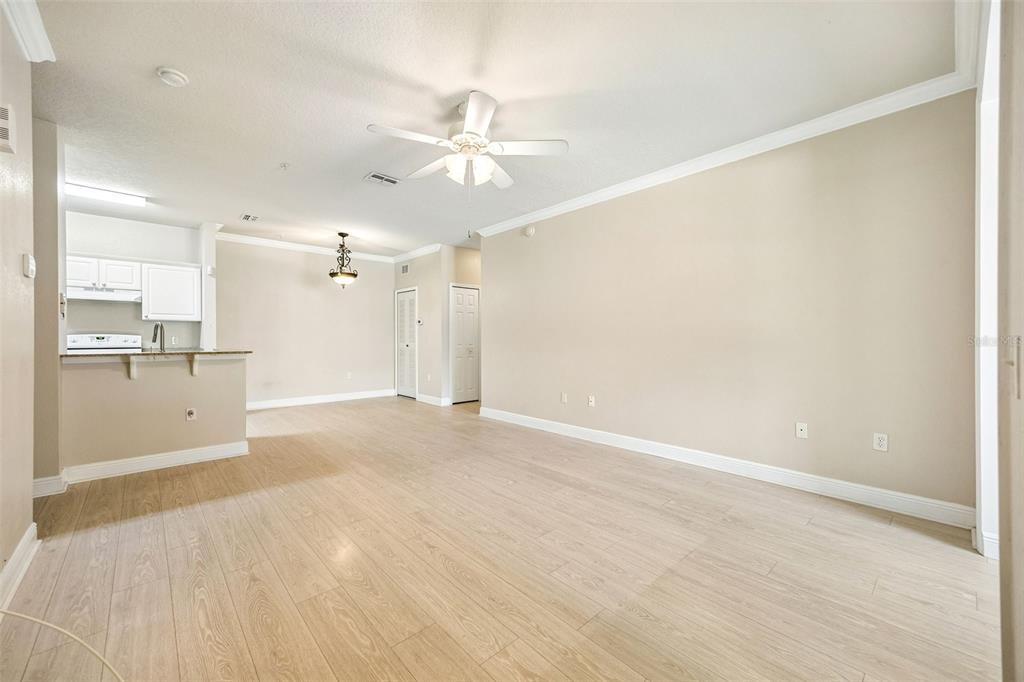 An open-concept living area features light wood-look flooring, a ceiling fan, and an adjacent kitchen — 405 SOUTHERN PECAN CIRCLE UNIT 108, WINTER GARDEN, FL