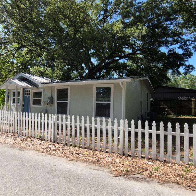 A single-story house with a light-colored exterior and a white picket fence — 7409 RHODE ISLAND DRIVE, TAMPA, FL