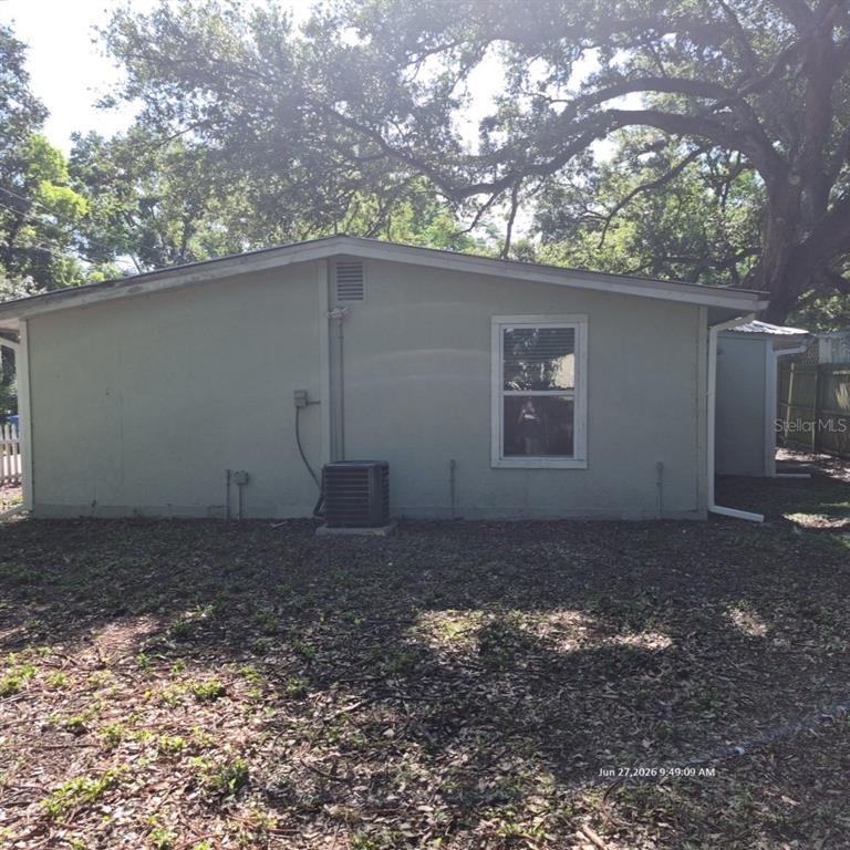 The exterior side of a house features a single window, an HVAC unit, and siding — 7409 RHODE ISLAND DRIVE, TAMPA, FL