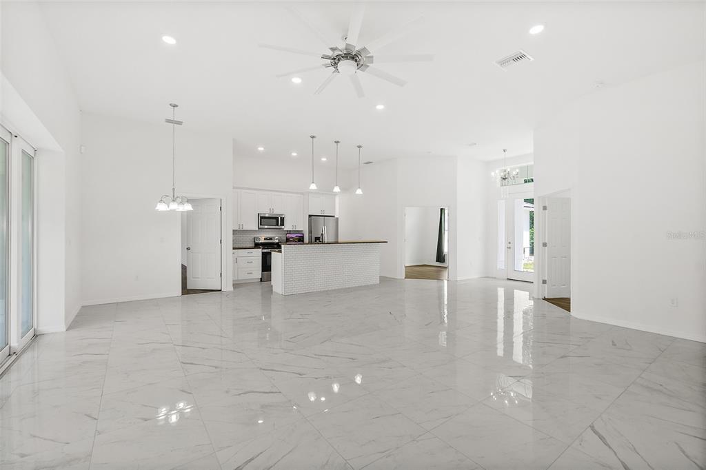 A bright, open-concept living area features white marble-look tile floors and a modern kitchen island — 1370 BUCKLES ROAD, PIERSON, FL