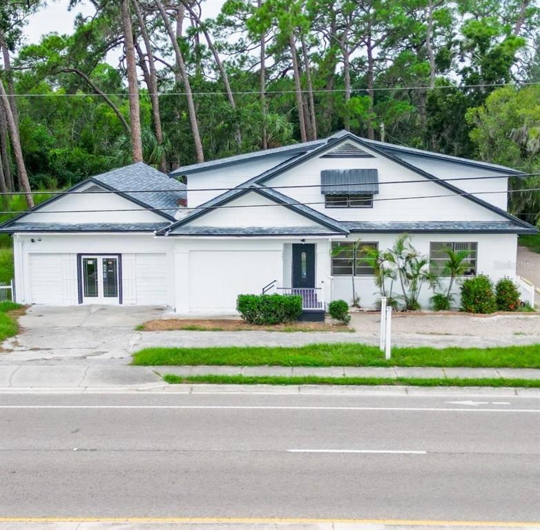 A white house with a dark roof and a front-facing garage sits near a road — 301 N US HIGHWAY 41, RUSKIN, FL