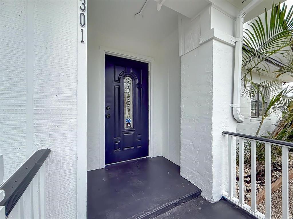 A dark blue front door with a glass insert sits under a covered porch — 301 N US HIGHWAY 41, RUSKIN, FL