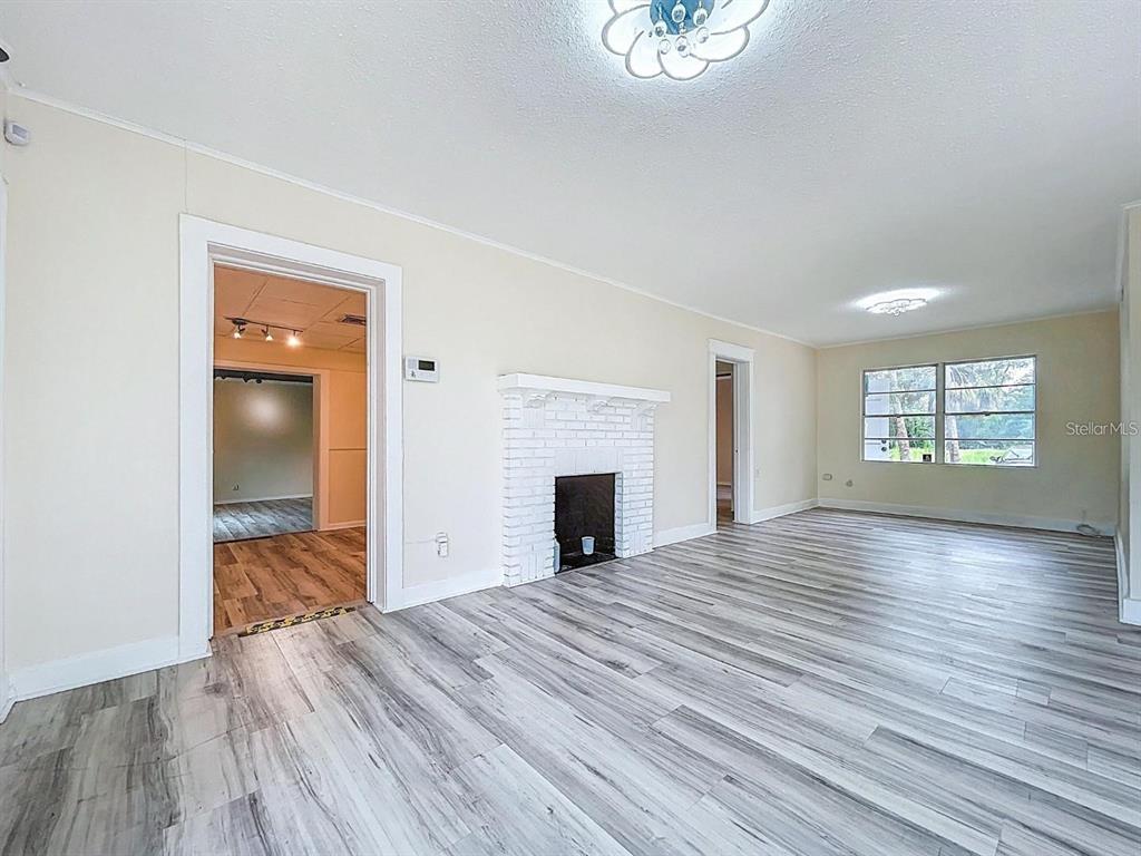 A living room features light wood-look flooring, a white brick fireplace, and two doorways — 301 N US HIGHWAY 41, RUSKIN, FL