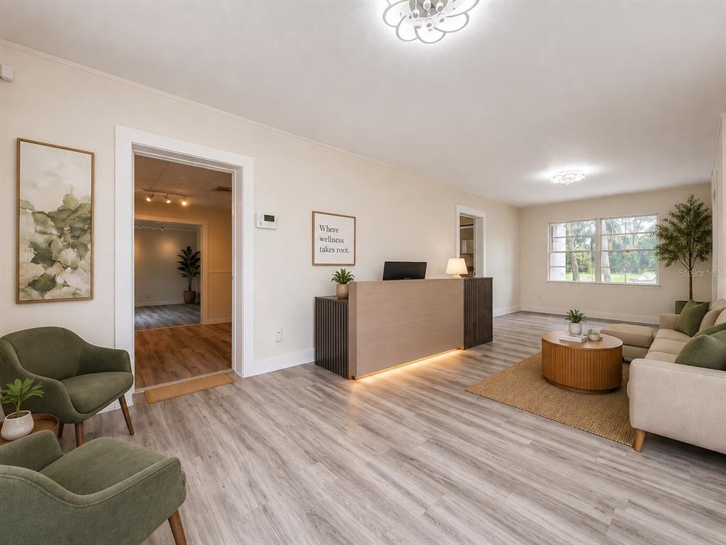 A reception area features a wooden desk, green armchairs, light wood flooring, and large windows — 301 N US HIGHWAY 41, RUSKIN, FL