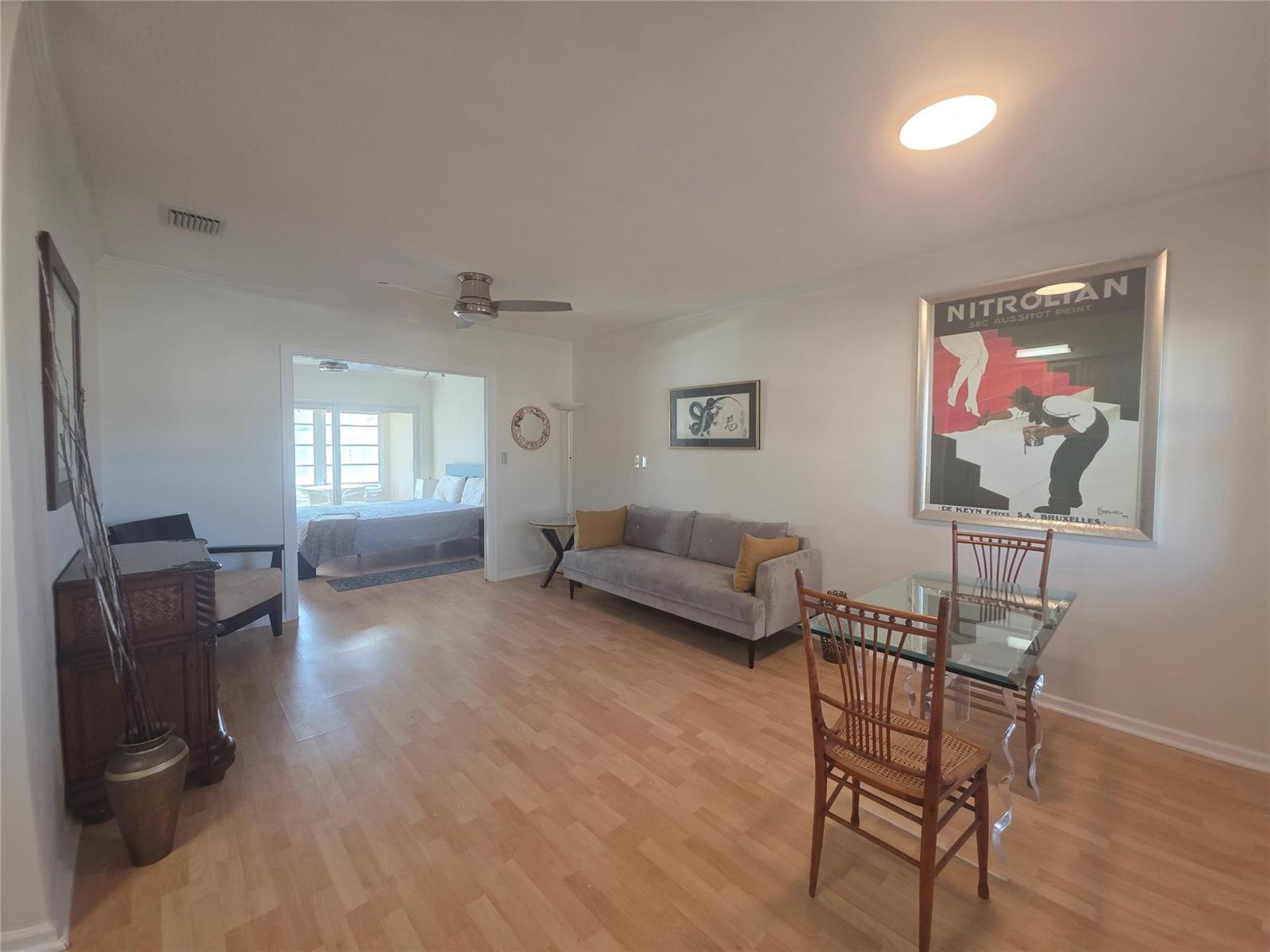 A living and dining area with wood-look flooring, a grey sofa, and a glass table — 2131 NE 42nd Court # 208e, Lighthouse Point FL 33064, LIGHTHOUSE POINT, FL