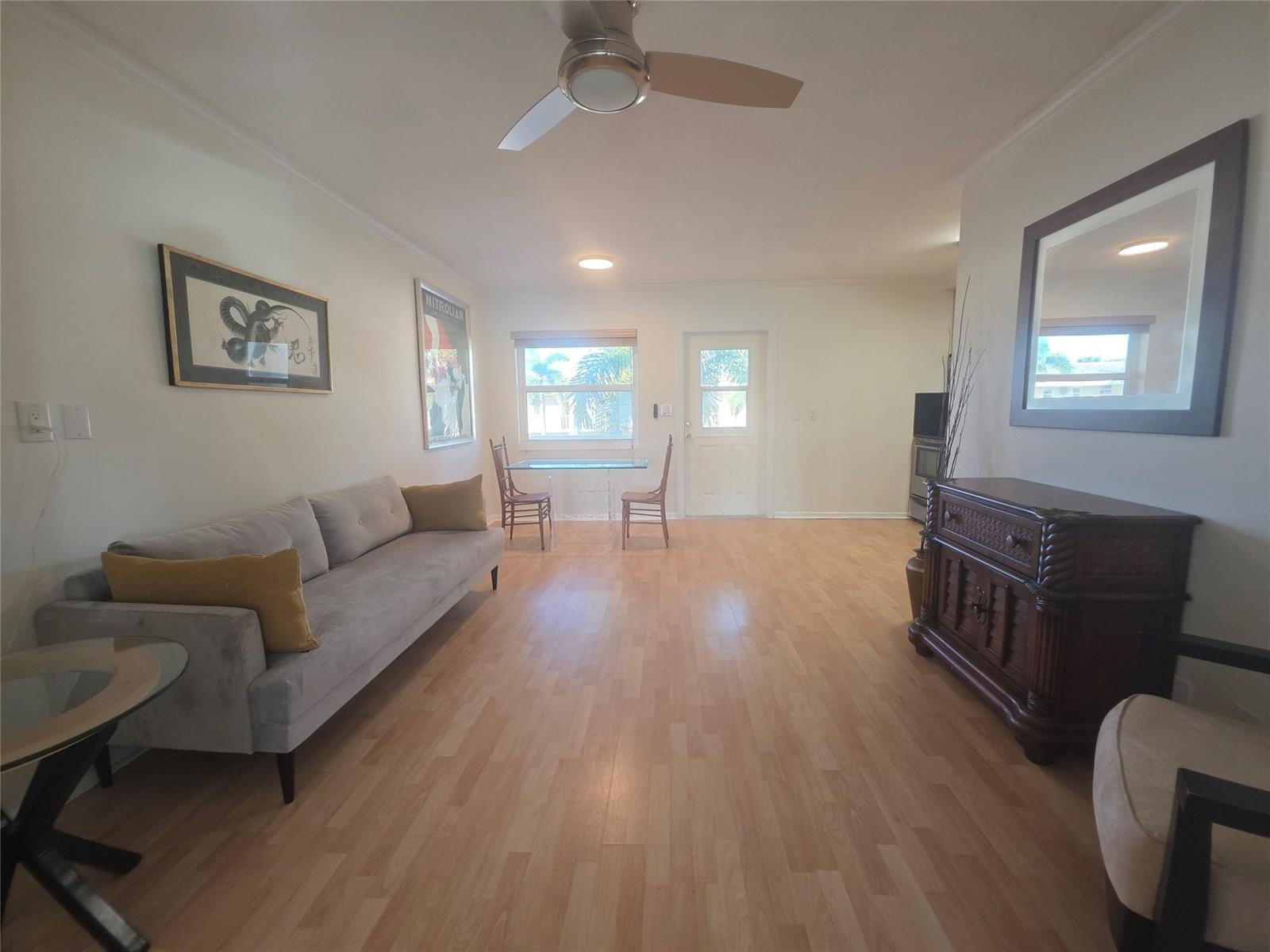 A living room with light wood floors, a grey sofa, and a dining area — 2131 NE 42nd Court # 208e, Lighthouse Point FL 33064, LIGHTHOUSE POINT, FL
