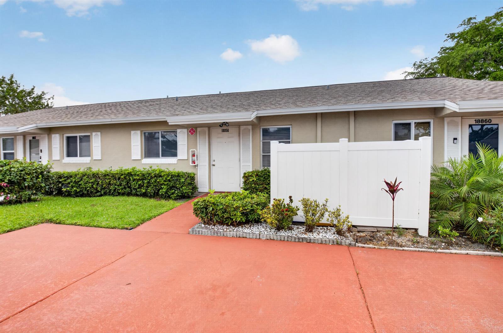 A single-story building exterior features a red concrete driveway, white doors, and privacy fencing — 18856 Argosy Drive # C, Boca Raton FL 33496, BOCA RATON, FL