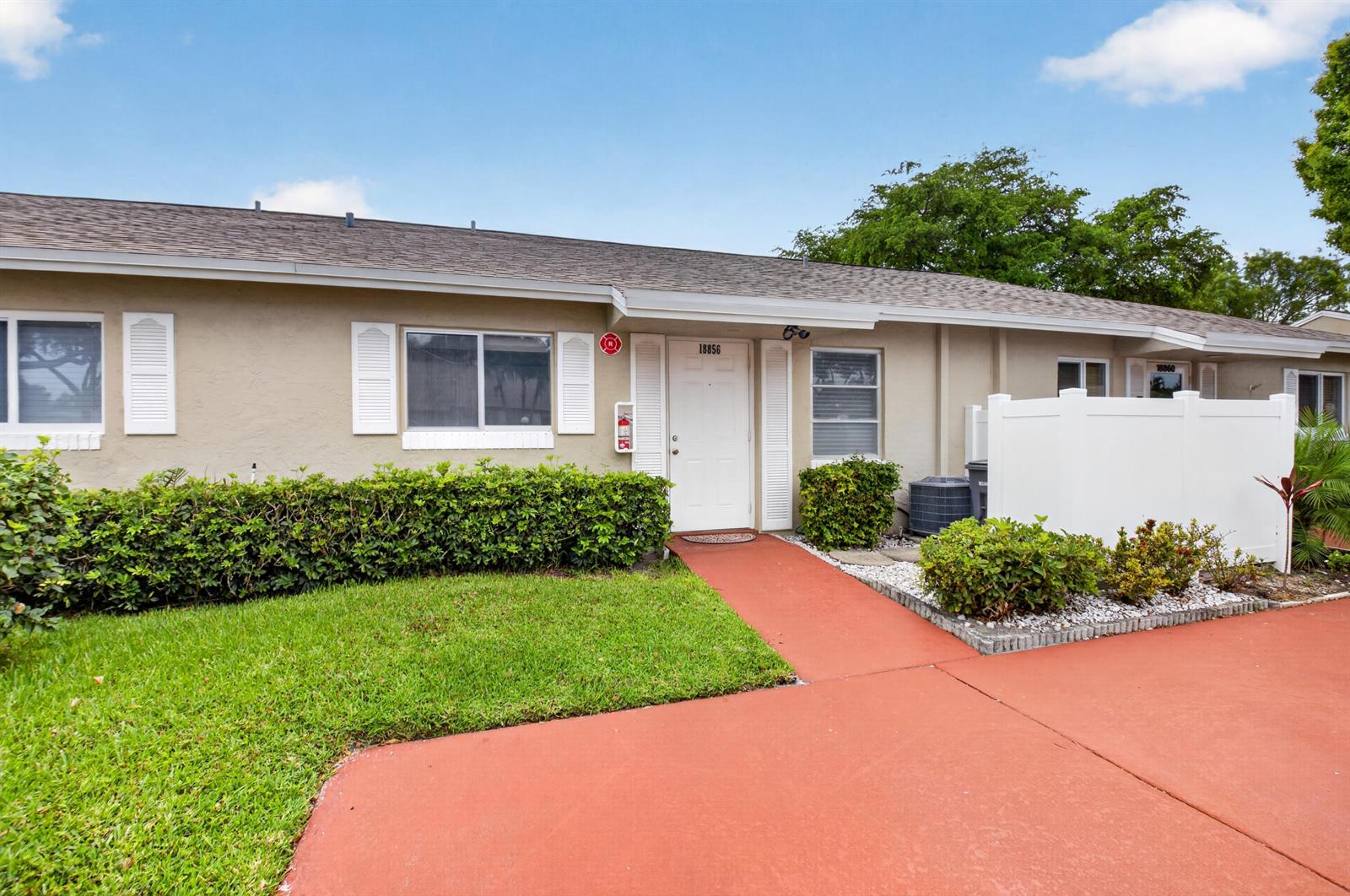 A single-story residential building with a tan stucco exterior, white shutters, and a red walkway — 18856 Argosy Drive # C, Boca Raton FL 33496, BOCA RATON, FL