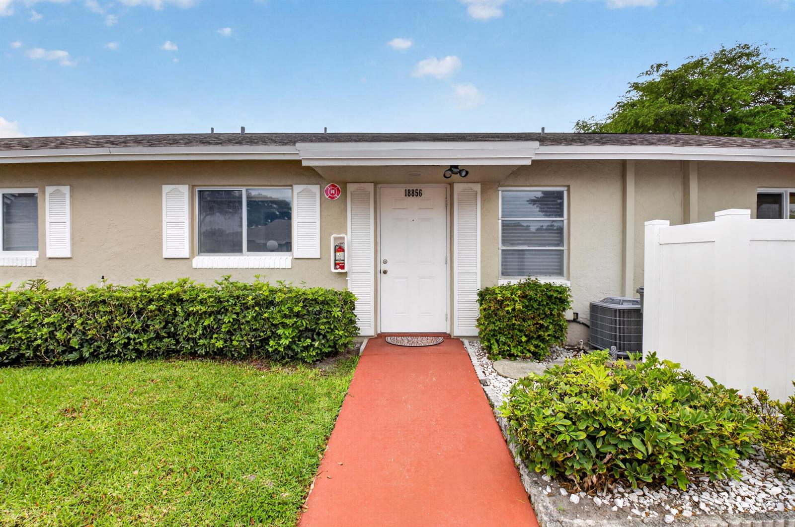 The exterior of a single-story residence features a white front door and a red walkway — 18856 Argosy Drive # C, Boca Raton FL 33496, BOCA RATON, FL
