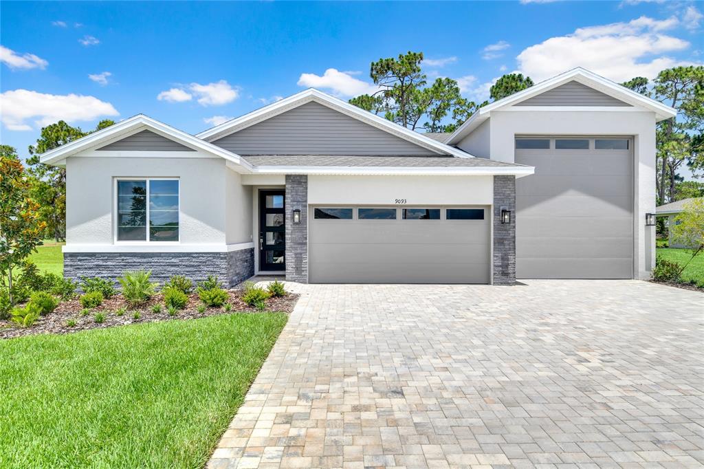 A single-story house with a gray garage, stone accents, and a paved driveway — 9093 PLAYERS DRIVE, WEEKI WACHEE, FL