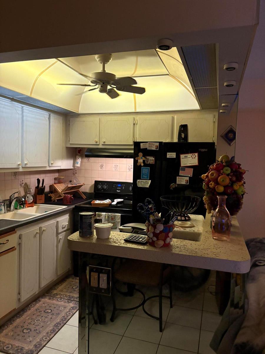 A kitchen with white cabinets, black appliances, a ceiling fan, and a breakfast bar — 3 Kent A, West Palm Beach FL 33417, WEST PALM BEACH, FL