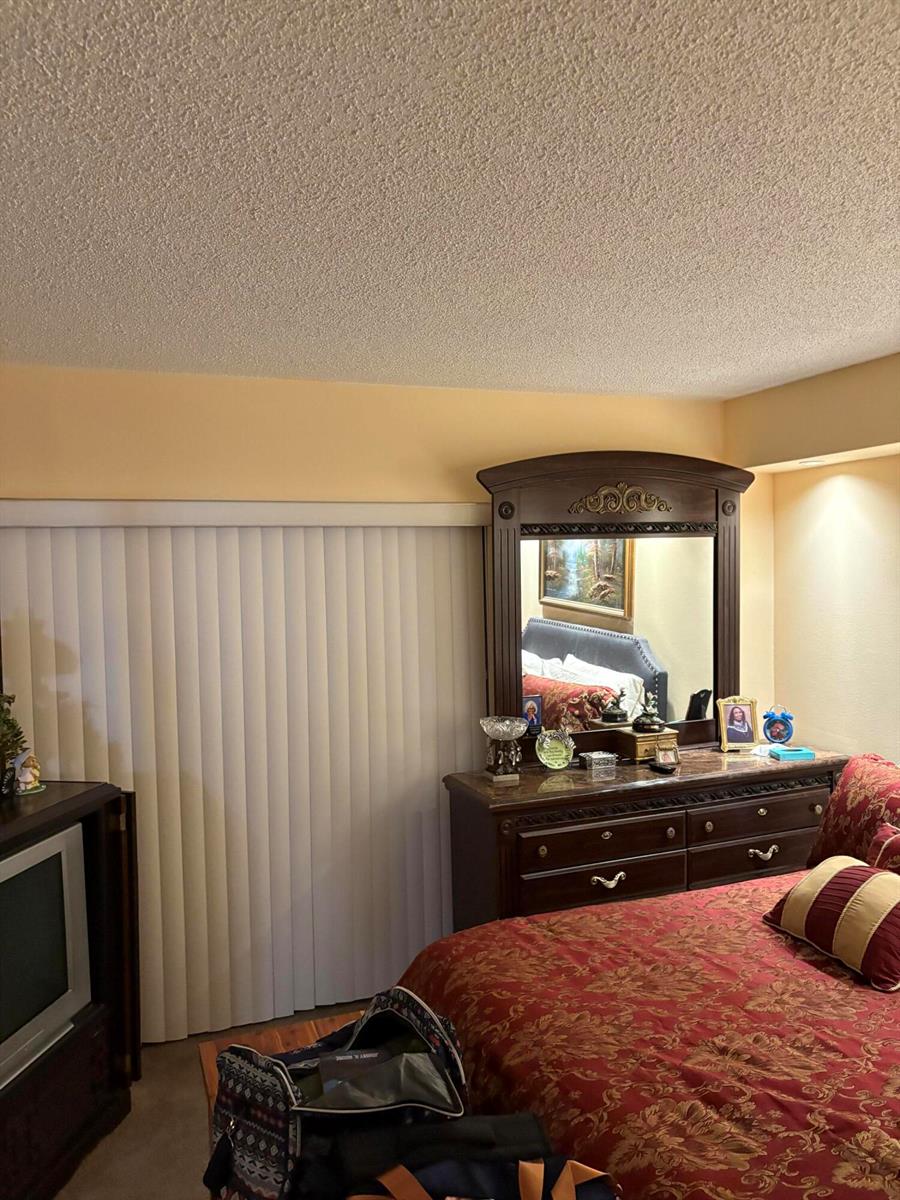 A bedroom features a wooden dresser with a mirror, a bed, and vertical window blinds — 3 Kent A, West Palm Beach FL 33417, WEST PALM BEACH, FL