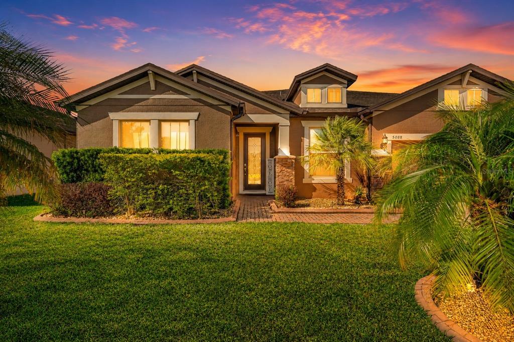A single-story house with a brown stucco exterior, a brick walkway, and a manicured lawn — 5088 HARTWELL COURT, ST CLOUD, FL