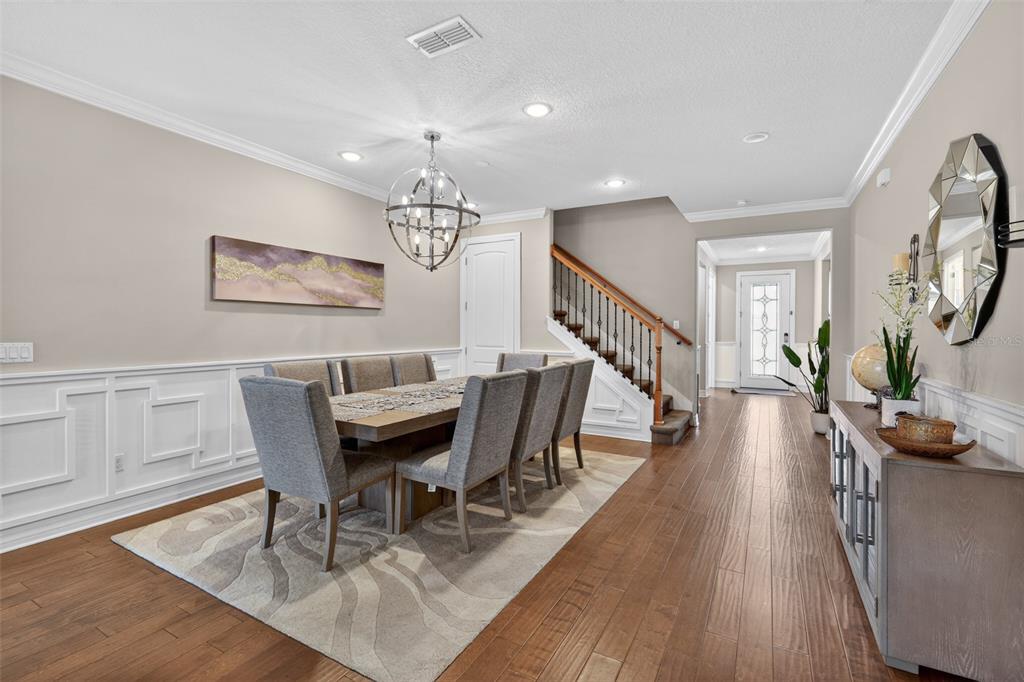 A dining room features a wooden table, gray upholstered chairs, a chandelier, and hardwood floors — 5088 HARTWELL COURT, ST CLOUD, FL