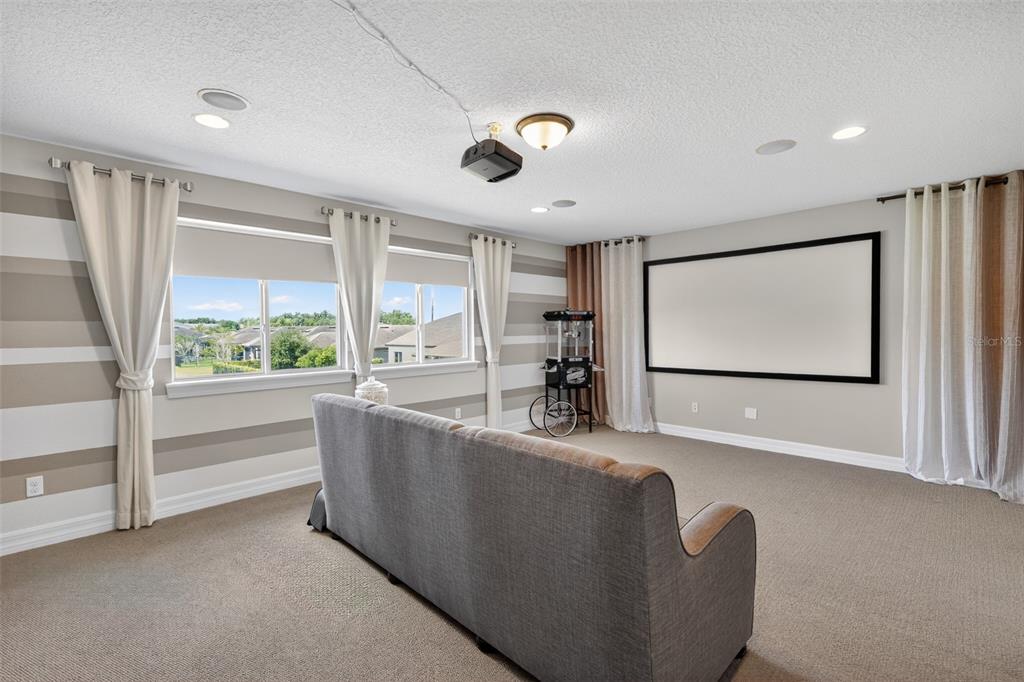 A home theater room features a projector, a large screen, a sofa, and striped walls — 5088 HARTWELL COURT, ST CLOUD, FL