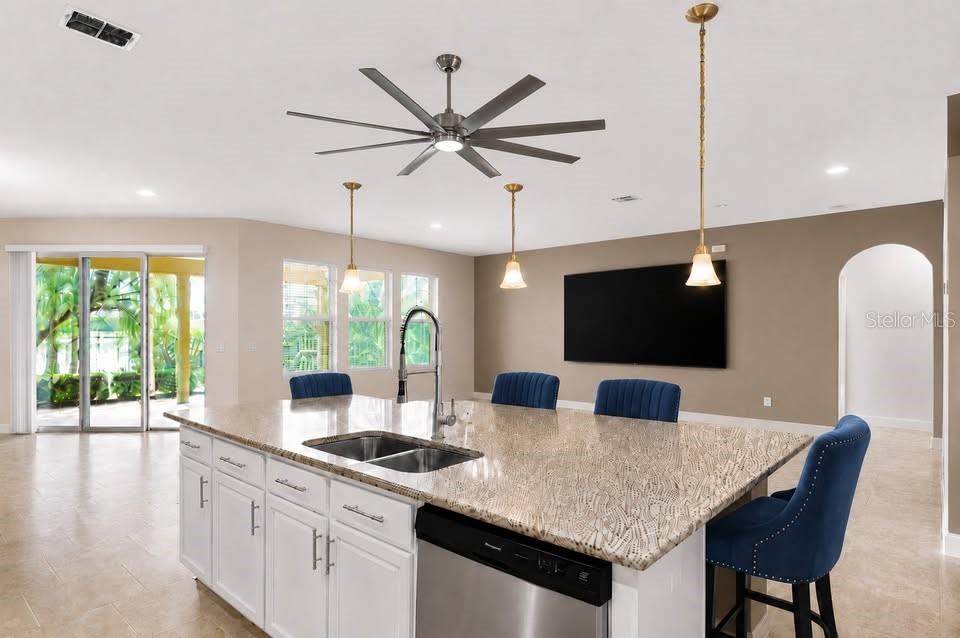 A kitchen island with granite countertops and blue chairs sits in an open-concept living space — 1316 LAKE BATON DRIVE, DELTONA, FL