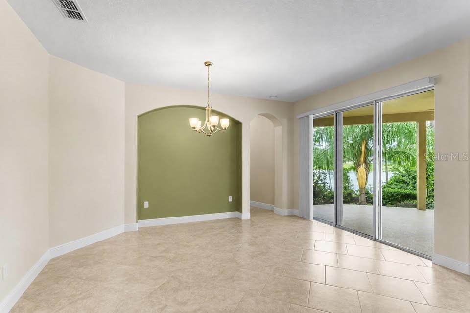 A dining area features tile flooring, a green arched accent wall, and sliding glass patio doors — 1316 LAKE BATON DRIVE, DELTONA, FL