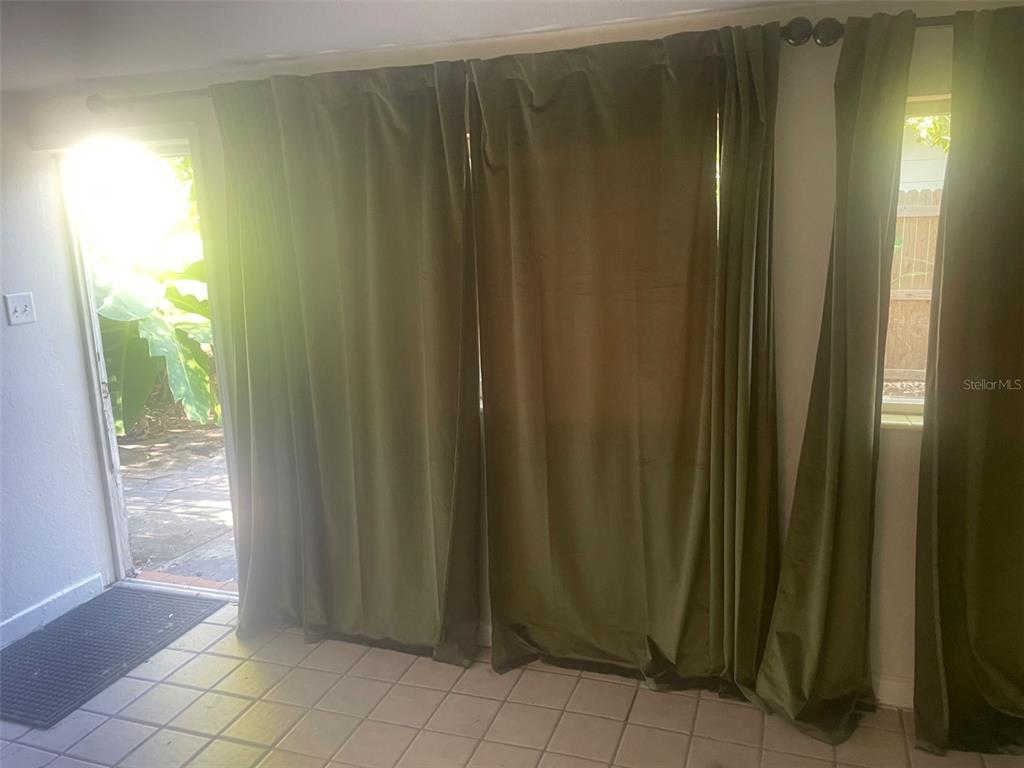 A room with tiled floors, olive green curtains, and a glass door leading outside — 776 27TH AVENUE N UNIT 2, ST PETERSBURG, FL