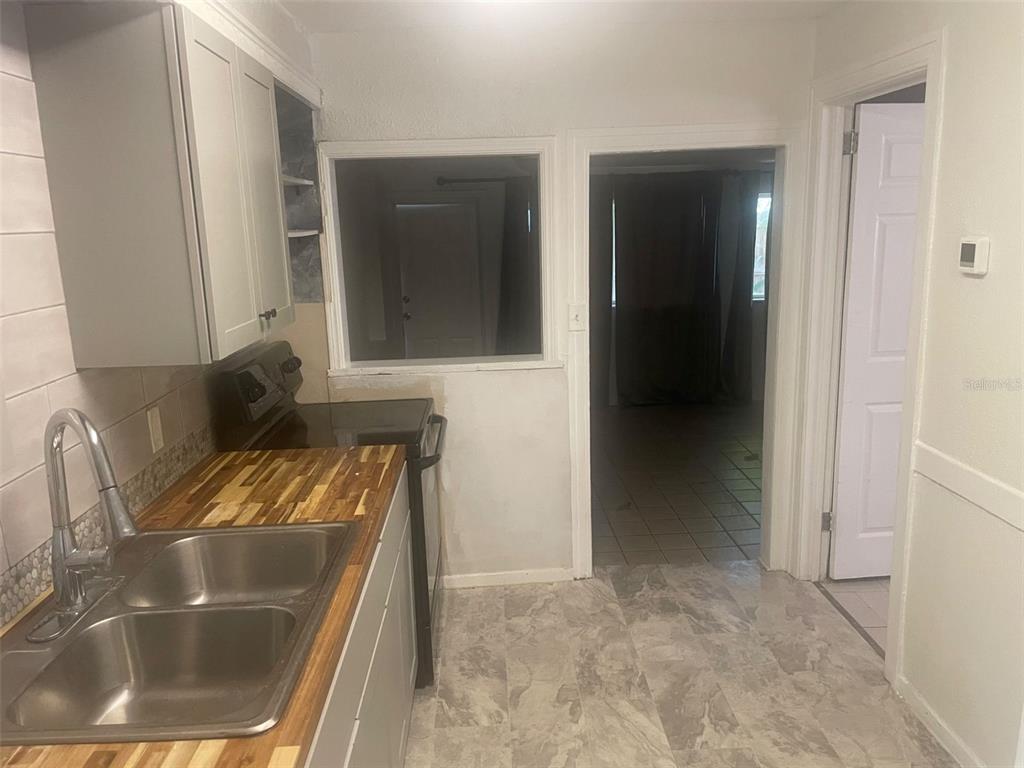 A kitchen features light gray cabinets, a butcher block countertop, a double sink, and tile flooring — 776 27TH AVENUE N UNIT 2, ST PETERSBURG, FL