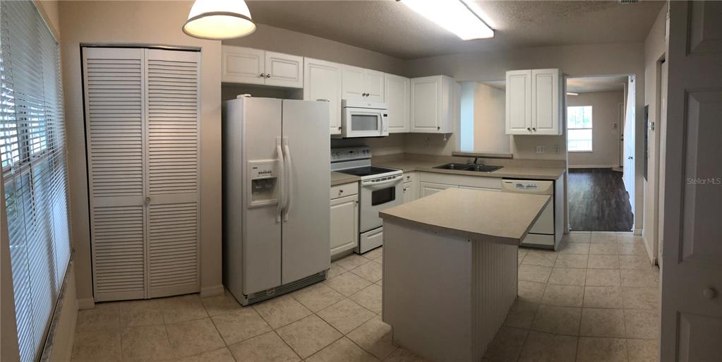 An empty room features dark wood-look flooring, light-colored walls, two windows, and a ceiling fan — 2375 SW 42ND WAY UNIT 160, GAINESVILLE, FL