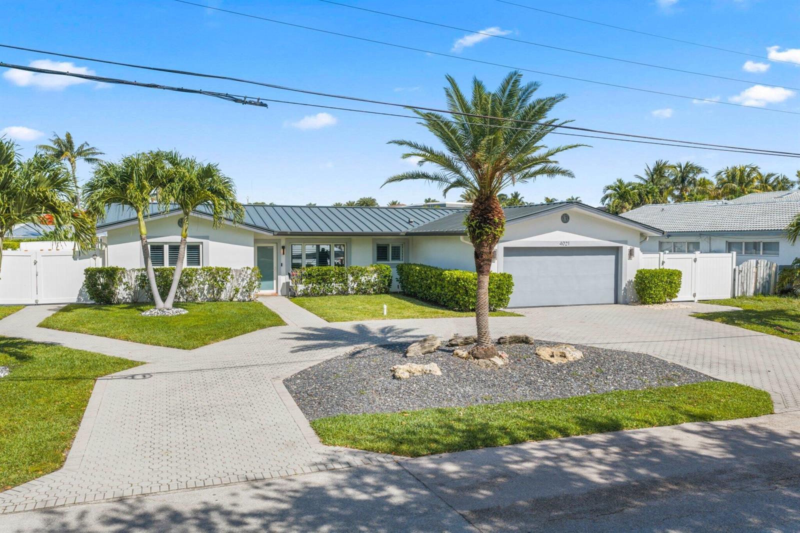 A single-story house with a metal roof, a paved driveway, and a central palm tree — 4021 NE 27th Terrace, Lighthouse Point FL 33064, LIGHTHOUSE POINT, FL