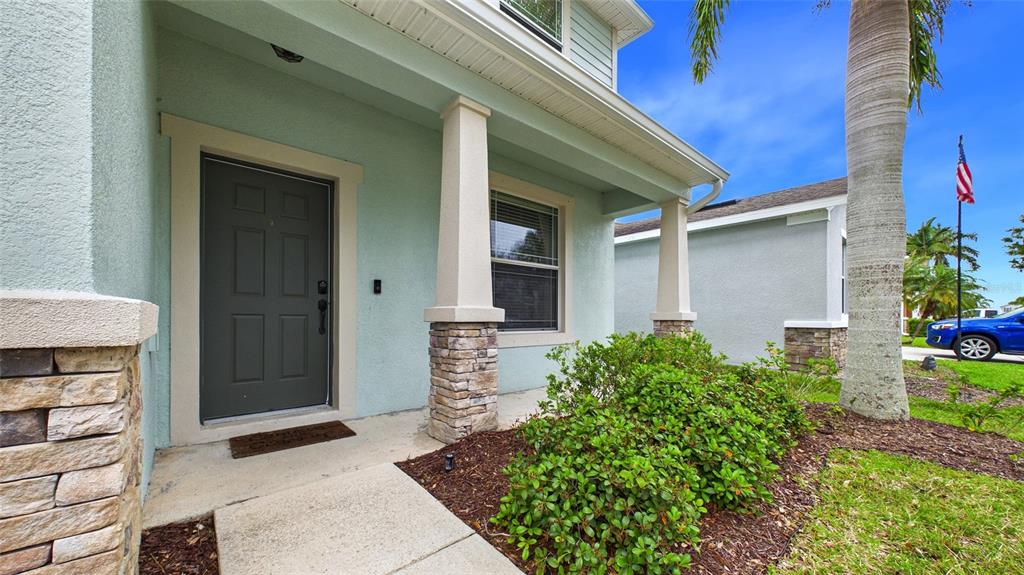The exterior of a house features a covered porch, stone pillars, and a front door — 601 19TH STREET NW, RUSKIN, FL