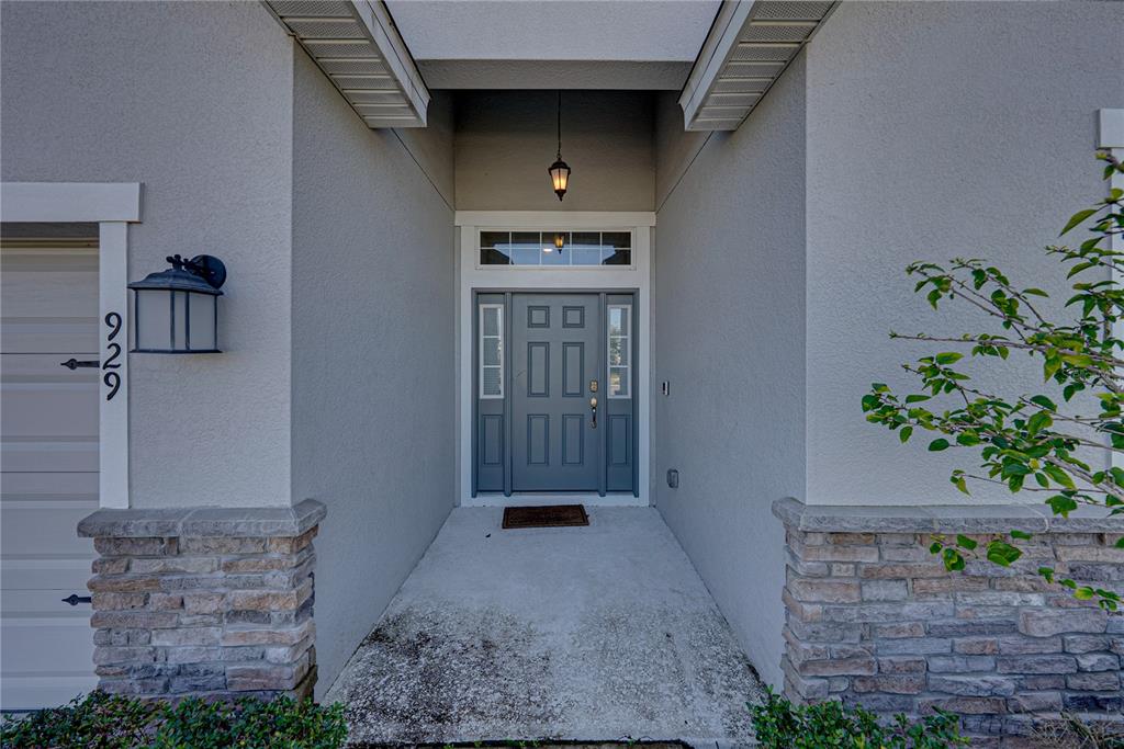 The exterior front entryway features a gray door with sidelights and stone veneer accents — 929 MONTGOMERY LANE, POLK CITY, FL
