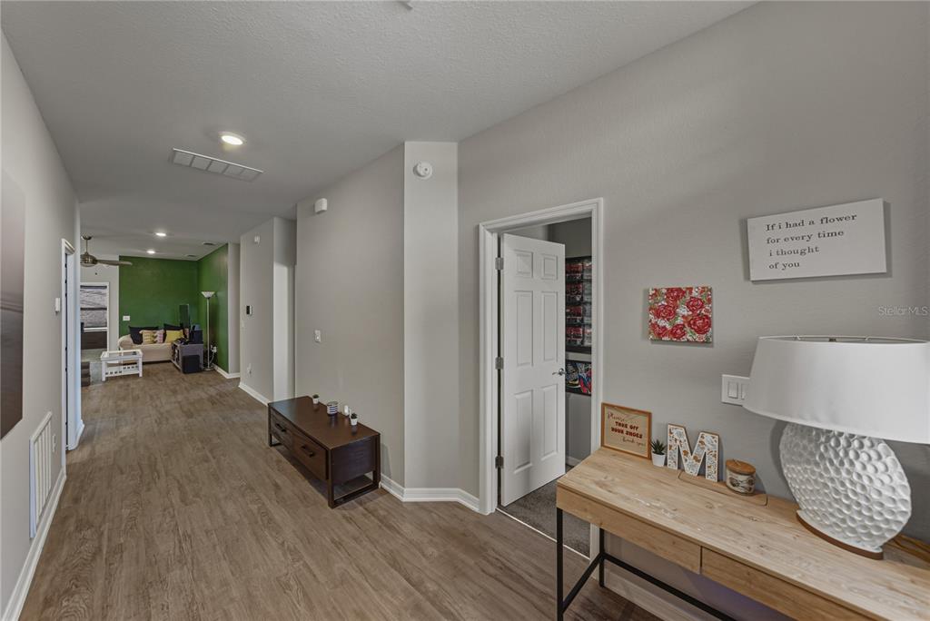 A hallway with wood-look flooring leads to a living area with a green accent wall — 929 MONTGOMERY LANE, POLK CITY, FL