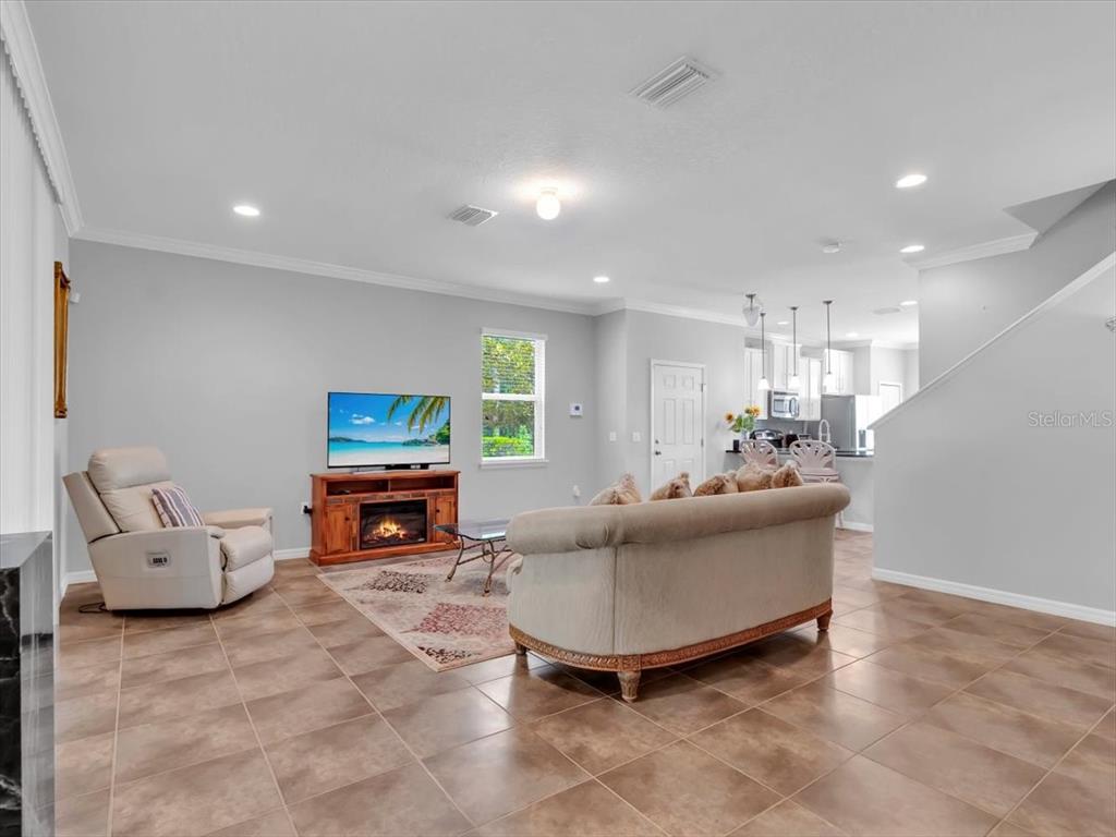 A living room with tile floors, a beige sofa, a recliner, and a fireplace console — 13901 RIVER WILLOW PLACE, TAMPA, FL