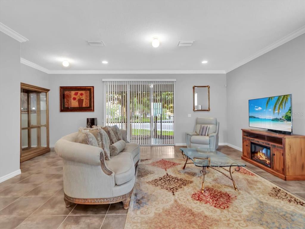 A living room features tile flooring, a sofa, a glass coffee table, and a television — 13901 RIVER WILLOW PLACE, TAMPA, FL