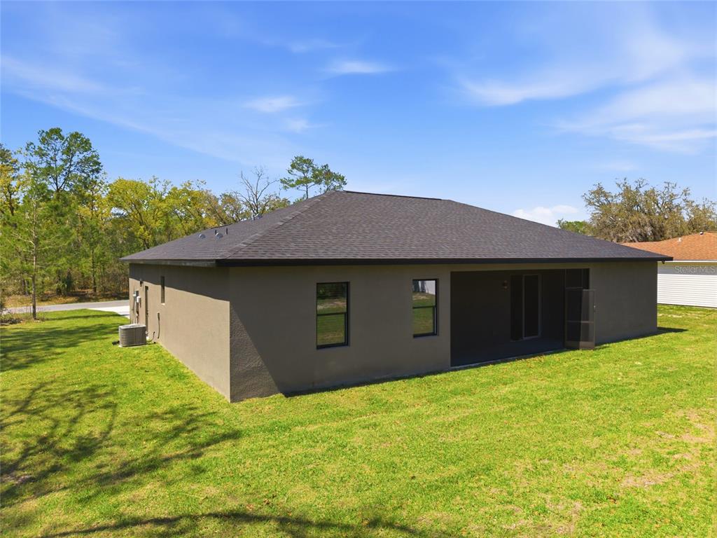 The exterior of a single-story house with a dark roof and a screened-in back porch — 14919 SW 46TH CIRCLE, OCALA, FL