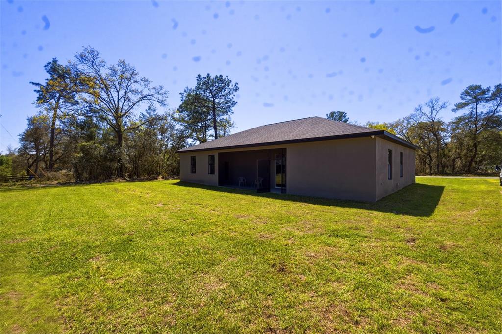 The exterior of a single-story house with a covered patio sits on a grassy lot — 14919 SW 46TH CIRCLE, OCALA, FL