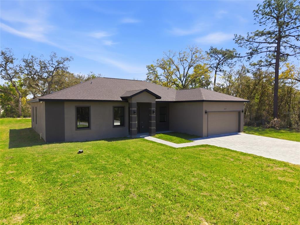 A single-story house with a gray stucco exterior, a dark shingled roof, and an attached garage — 14919 SW 46TH CIRCLE, OCALA, FL