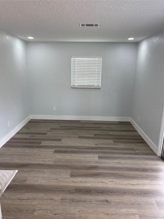 An empty room features light blue walls, white trim, and wood-look vinyl plank flooring — 977 E NORMANDY BOULEVARD, DELTONA, FL