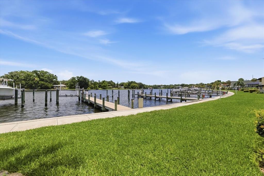 A grassy lawn borders a concrete walkway next to a canal with multiple boat docks — 2424 W TAMPA BAY BOULEVARD UNIT G104, TAMPA, FL