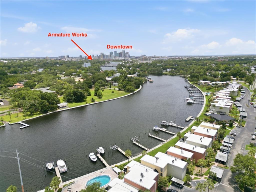 An aerial view shows a river with boat docks, residential buildings, and a distant city skyline — 2424 W TAMPA BAY BOULEVARD UNIT G104, TAMPA, FL