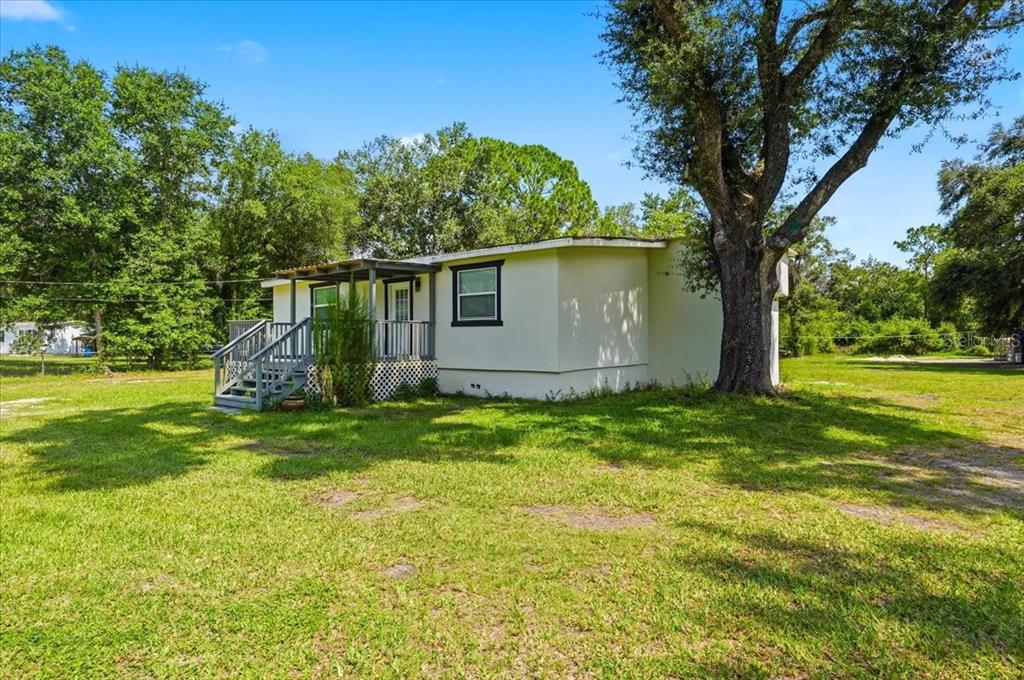 A single-story house with a wooden deck and a large tree in the yard — 303 WILDLIFE TRAIL, LAKELAND, FL