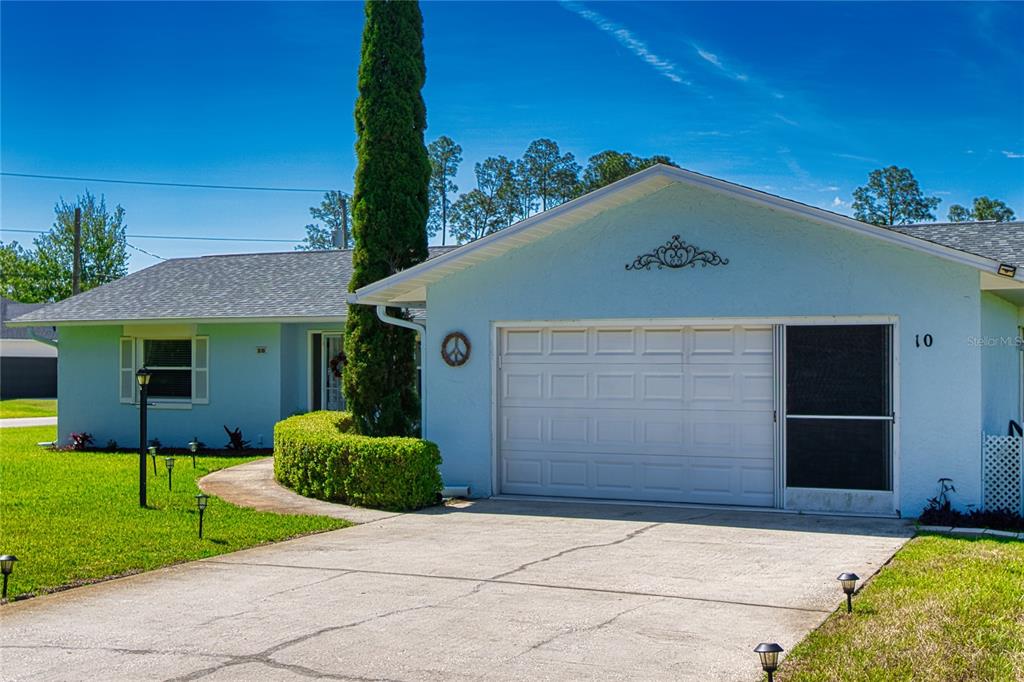 A light blue single-story house features a two-car garage, a concrete driveway, and landscaping — 10 ROCKWELL LANE, PALM COAST, FL