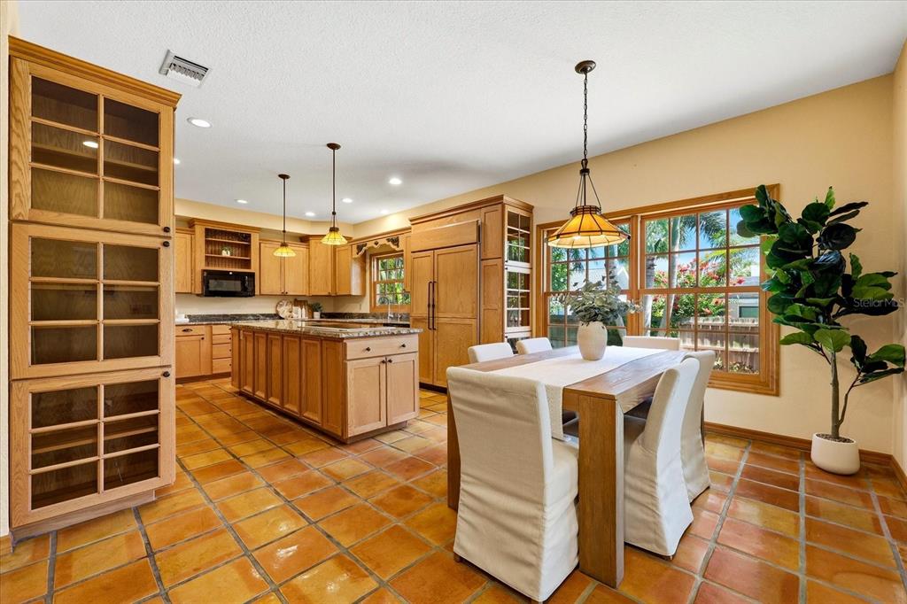 A kitchen and dining area with light wood cabinets, a center island, and terracotta flooring — 2917 SANDPIPER PLACE, CLEARWATER, FL