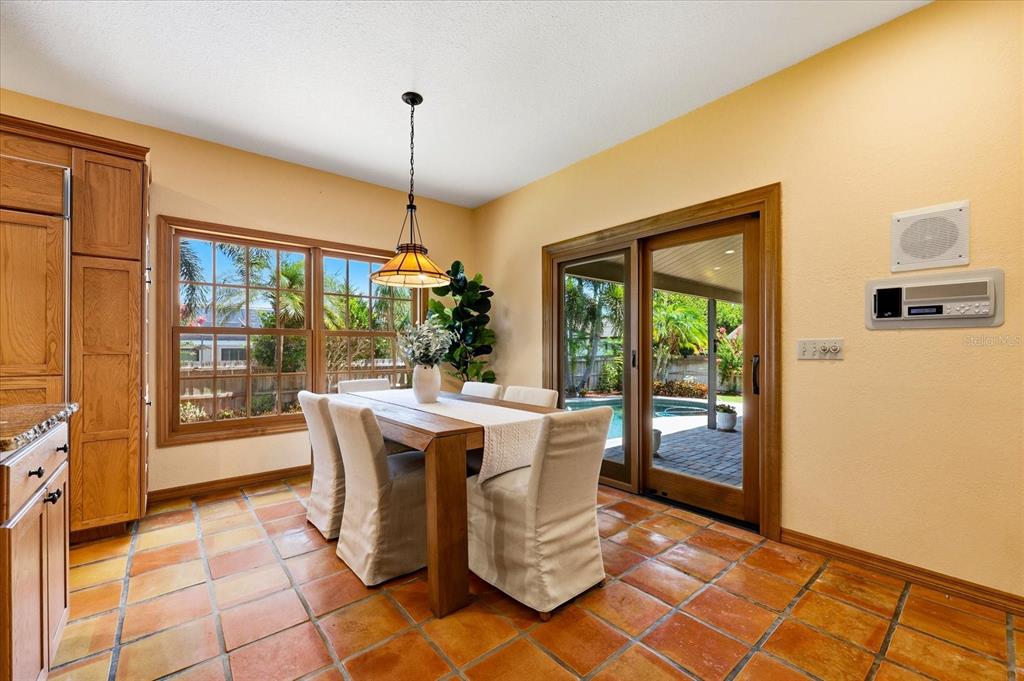 A dining room features a wooden table, slipcovered chairs, tile flooring, and sliding glass doors — 2917 SANDPIPER PLACE, CLEARWATER, FL